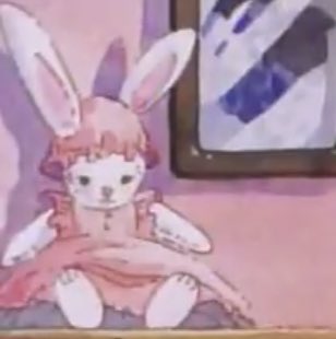 A white, plush rabbit in a pink bonnet and matching pink pinafore with frilled sleeves. A pink dress underneath, although it's hard to make out the details.