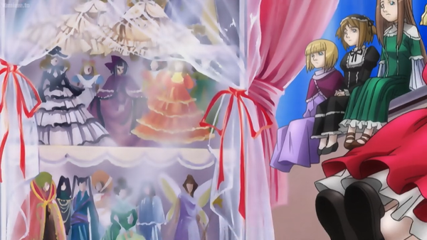 Numerous dolls decorating the shelves of doll-obsessed working woman Kusabue (Micchan) Mitsu's room, sitting on lace and behind lace curtains adorned with red ribbons, and some sitting in her windowsill, with the pink curtains pulled back, in the second season of Rozen Maiden.