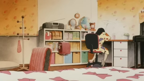 Still from the animated movie Junkers Come Here of Nozawa Hiromi's elegant bedroom. She has a curtain that matches the wallpaper on one side of her room, orange with stylized red tulips. The other  walls are white. Her bed has whtie bedding with a pink bow print. She has a plain white cabinet with three rows besides her, the bottom rows having colourful storage buckets, while the top and middle rows have books, one nook carrying her bags. Her big, red schoolbag hangs, likely off a stick-on hook. Over the cabinet, she has a boombox, a mirror, a globe, and a teddy bear. She has a coat rack behind her with only a small drawstring pink bag hanging from it. She sits at her desk, also plain white, with three drawers, and a wooden desktop.