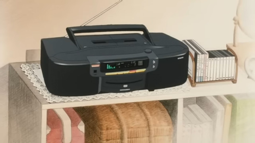 A close-up of the boombox, sitting on a rectangular doily, next to CD jewelcases.