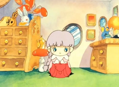 Still from the animated series Little Memole, depicting her very tiny bedroom (Memole is from a pixie-like race of aliens), with its colourful quilt on her bed with a big round headboard and footboard. She has wobbly and uneven, but charming, chest drawers (one engraved with hanging berries), a mushroom (toadstool?) for a side table, a little brass teapot, lights that look like berries, plushies that sit on top of one chest of drawers (a white rabbit and a chipmunk, the other smaller table bedside table with drawers has what appears to be a blue-grey mouse and an warmly glowing lamp with a shade), a light fixture that resembles lily-of-the-valley hangs over her bed.